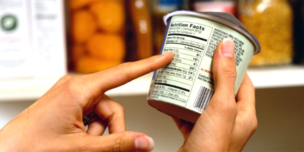 The Logical Trap of Hidden Sugars: How to Identify and Neutralize Silent Health Threats A person carefully reading a nutrition label on a food container to identify hidden sugars and calories