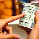 A person carefully reading a nutrition label on a food container to identify hidden sugars and calories
